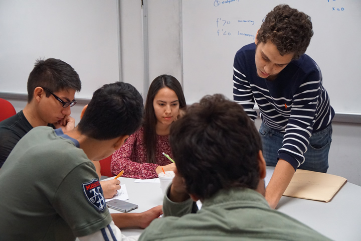 Four students receive tutoring from a another student