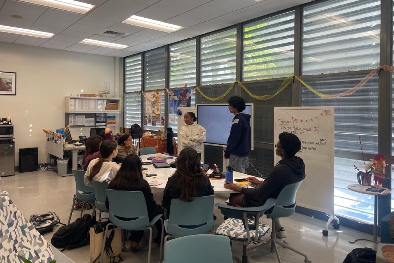 Four students receive tutoring from a another student