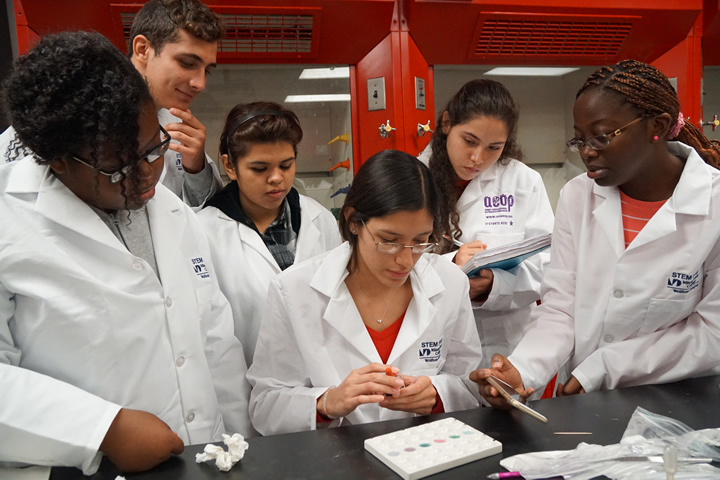 Students at a lab gather around an experiment